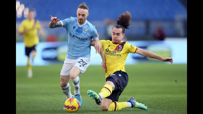 Cầu thủ Lazio dùng kỹ thuật cá nhân vượt qua hậu vệ Bologna trên sân cỏ